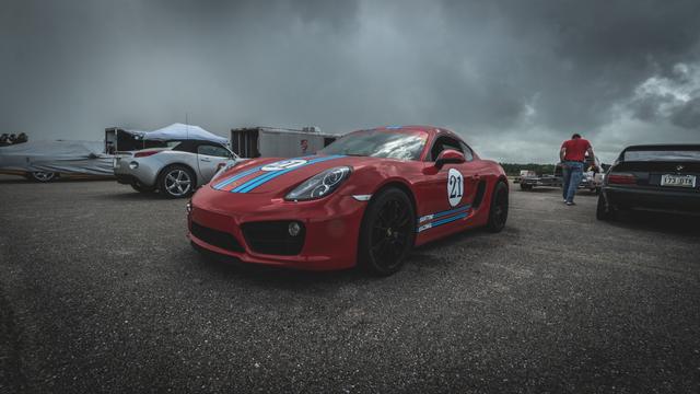 Porsche Cayman in Martini racing livery under a dark stormy sky