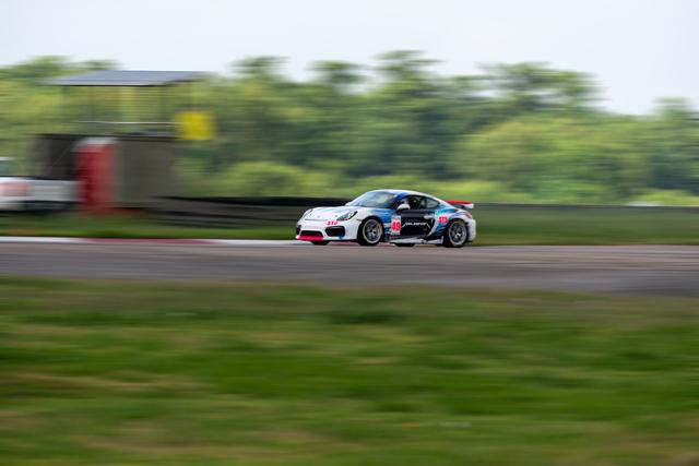 Panning shot of a white Porsche Cayman racing past a blurred track background
