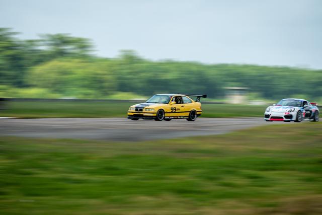 Panning shot of a yellow BMW M3 at speed on a racetrack with motion-blurred background