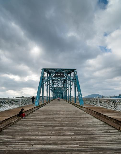 Blue Walnut Street Bridge pedestrian walkway under dramatic clouds in Chattanooga